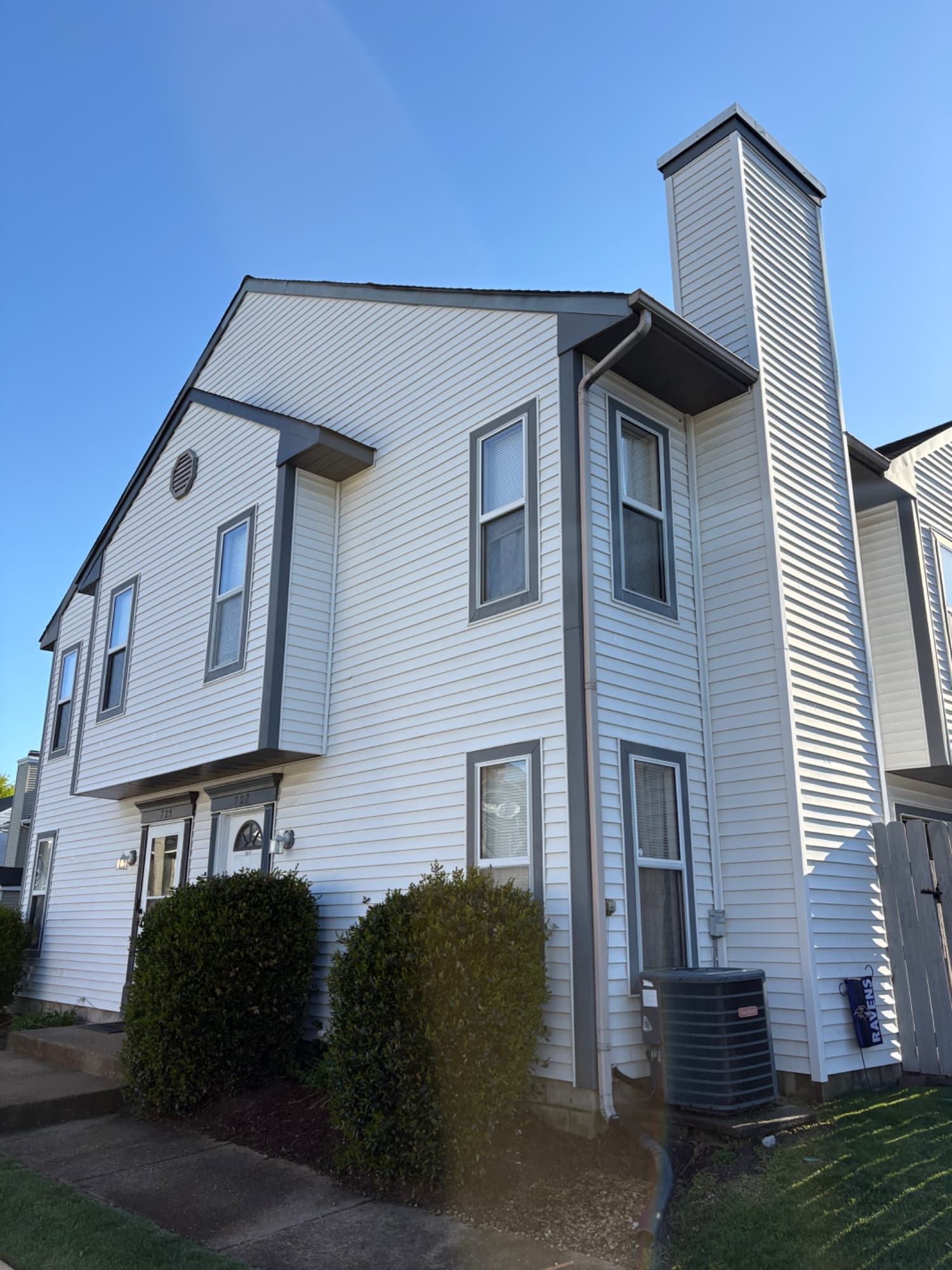 White townhouse exterior with a chimney and landscaped entry