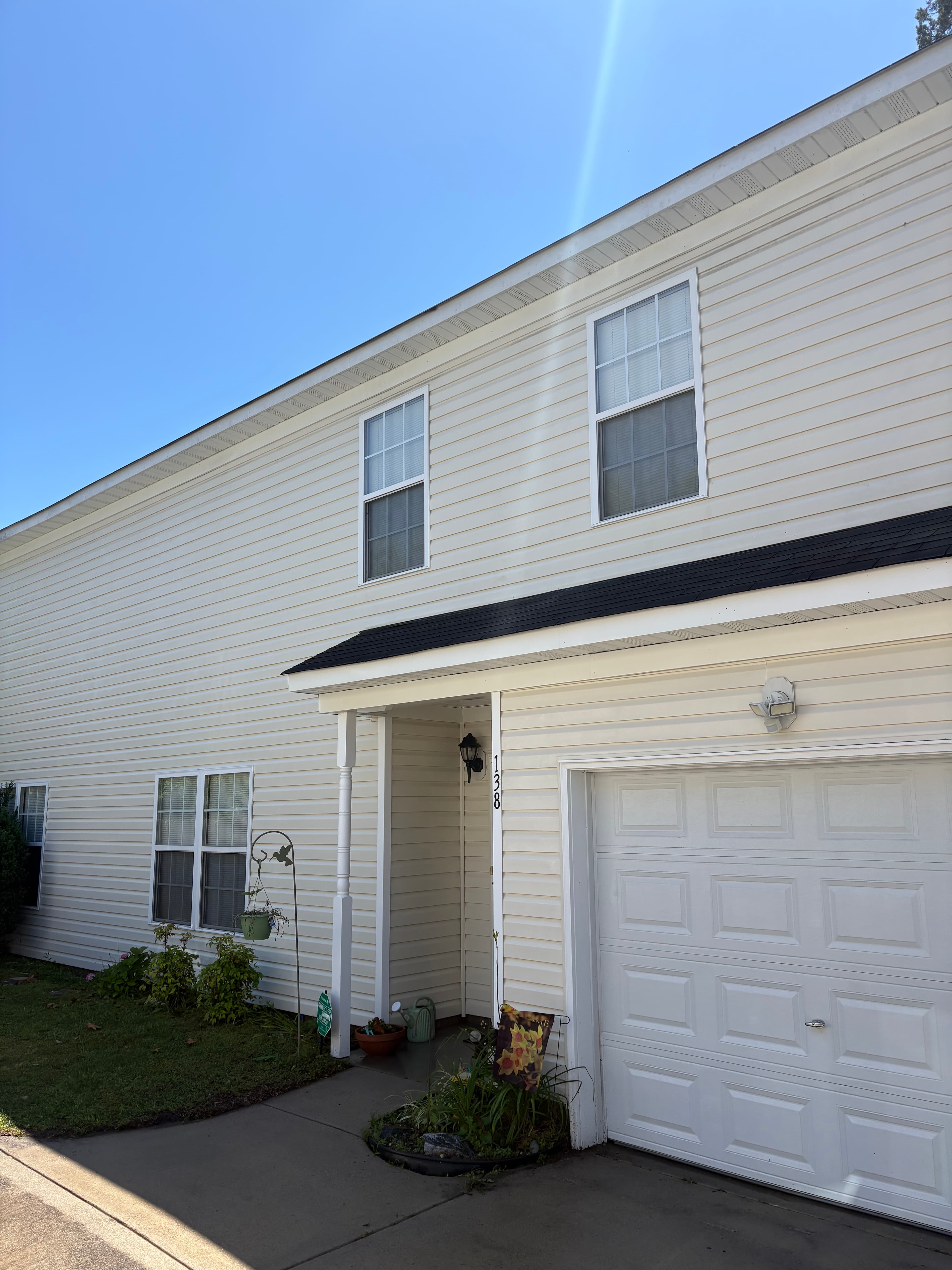 Light-sided home facade with windows, a covered entry, and a garage