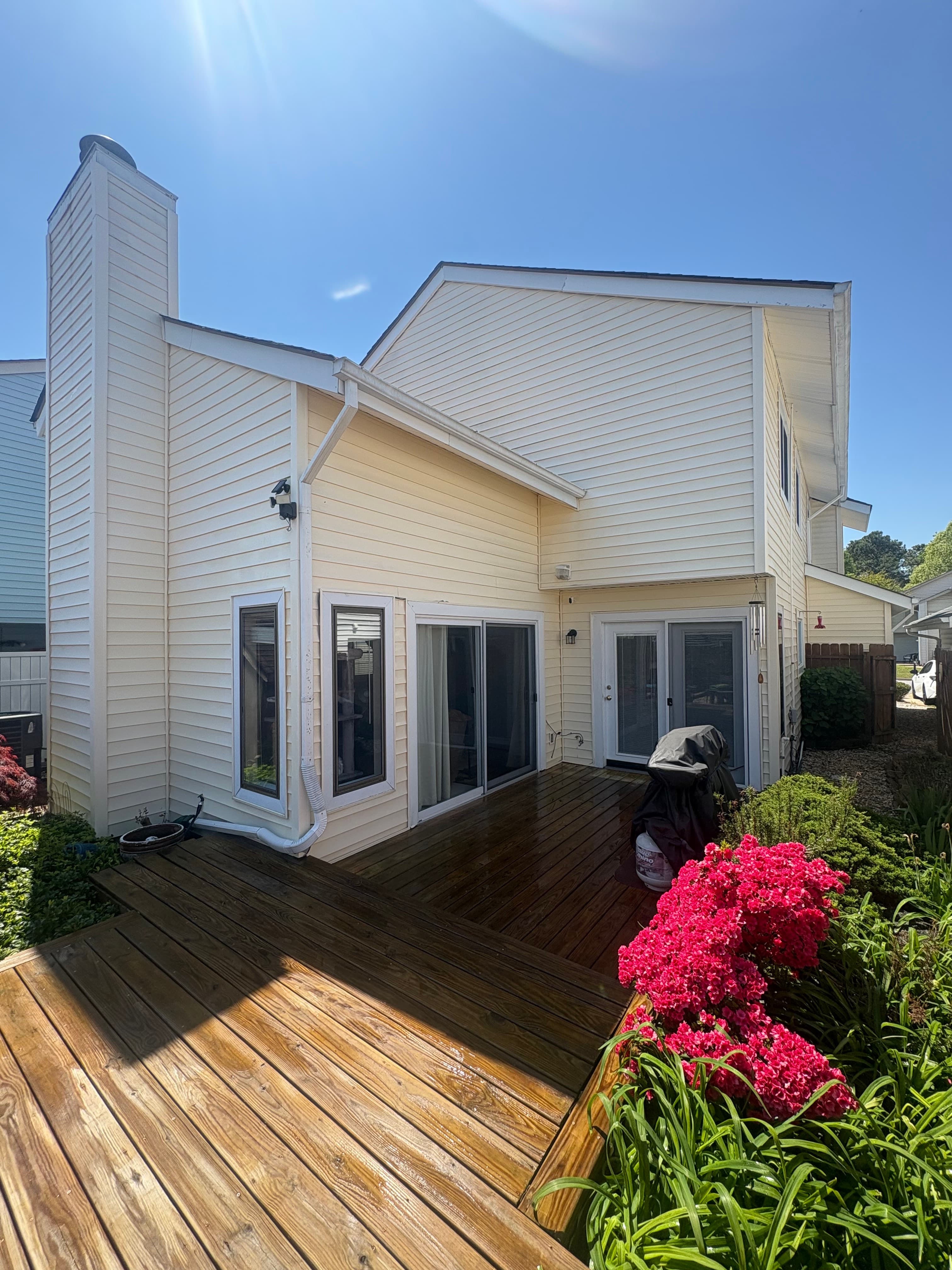 Light-colored home exterior with a deck and flowering shrubs